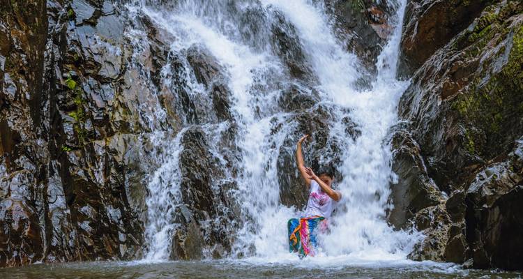 Woman enjoying a waterfall with water cascading around.