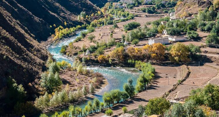 Vue aérienne d'une rivière sinueuse entourée de terres agricoles et d'arbres.