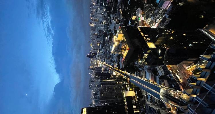 Luchtfoto van een stadslandschap bij schemering met wolkenkrabbers en goed verlichte straten.