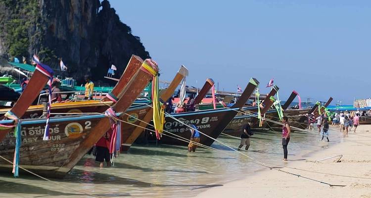 Traditionele longtailboten in helder water bij een tropisch strand.