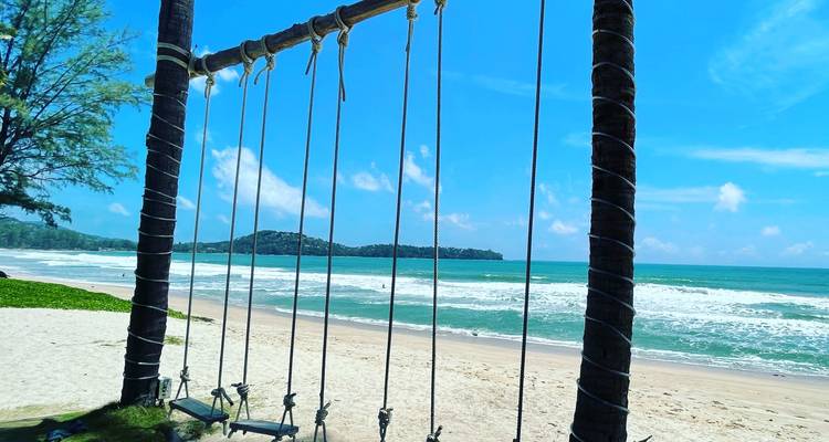 Een strandschommel met uitzicht op een pittoreske kustlijn met helder blauw water.