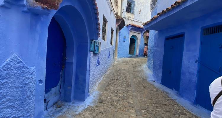 Blau gestrichene Gasse mit kunstvollen Türöffnungen und Steinpflaster.