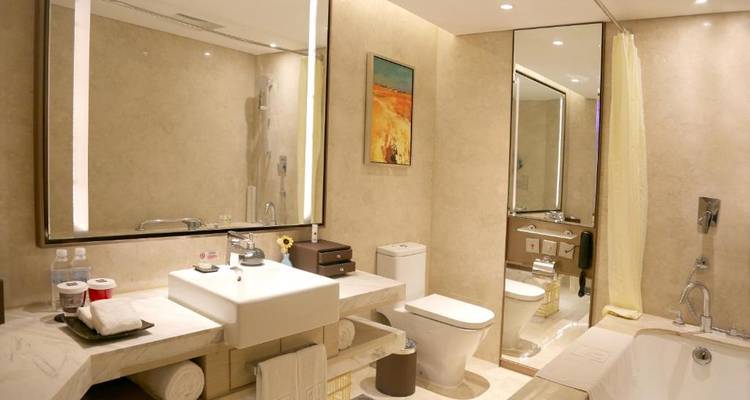 Salle de bain d'hôtel spacieuse avec un grand miroir, une baignoire et des œuvres d'art.