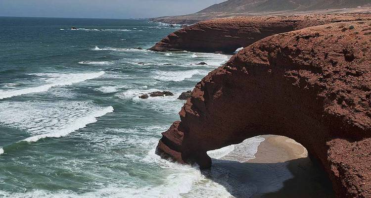 Rotsachtige kustlijn met een natuurlijke boog en golven bij Legzira.