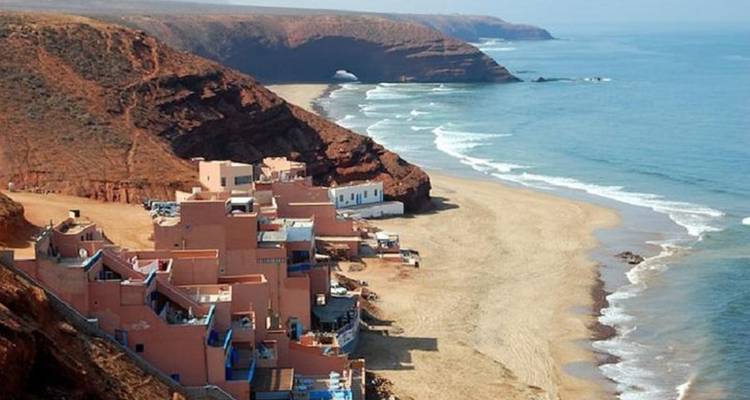 Kustgebied met rode kliffen en een zandstrand.