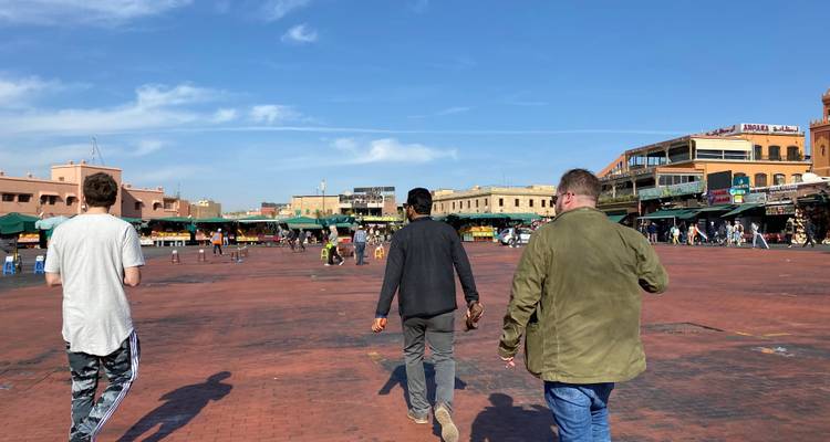 Three people walking in a bustling market square.
