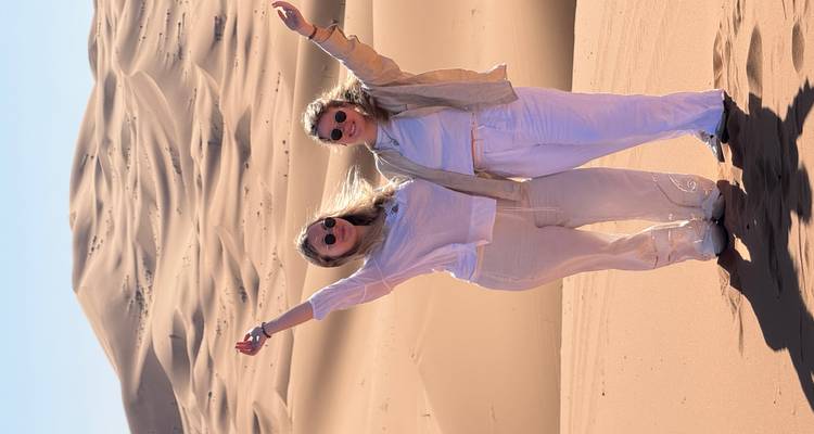 Deux femmes posant joyeusement dans les dunes du désert.