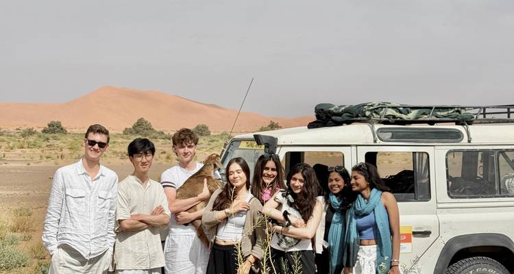 Groupe de personnes avec une jeep et un paysage désertique en arrière-plan.