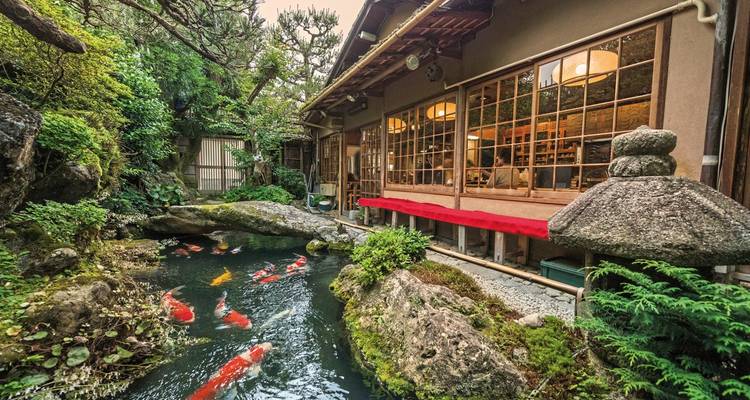 Traditional Japanese teahouse by a pond with koi fish.