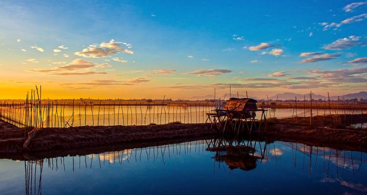 Eine ruhige Morgenansicht einer traditionellen Hütte am Wasser.