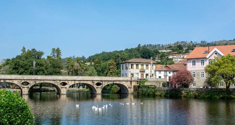 Un pittoresque pont de pierre au-dessus d'une rivière avec de la verdure environnante.