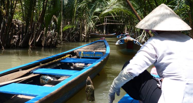 Een persoon in een traditionele boot die door een rivier navigeert.
