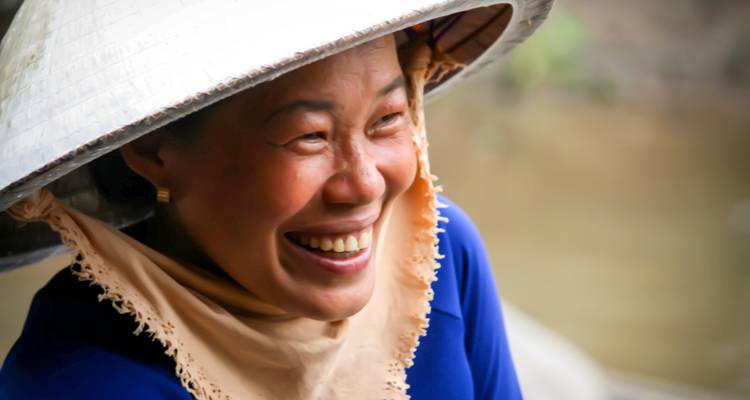 Closeup portret van een glimlachende vrouw die een kegelvormige hoed draagt.