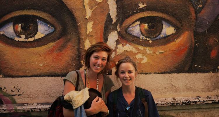 Deux personnes posant devant un mur avec de grands yeux peints.