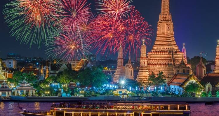 Vuurwerk boven een verlichte tempel en rivierscène.