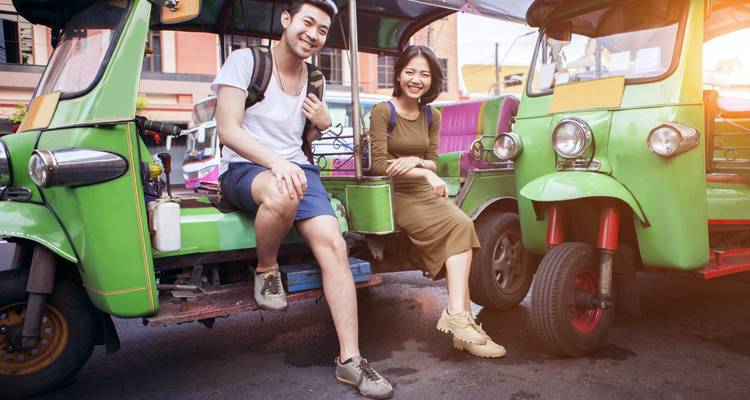 Twee mensen die op een tuk-tuk zitten in een stad.