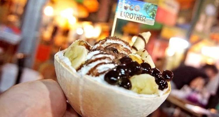 Hand die een dessert vasthoudt in een kokosschaal.