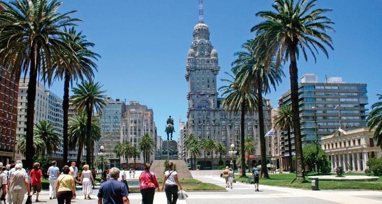 Een stadsplein met palmbomen en historische architectuur.
