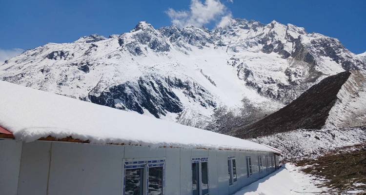 Sneeuwbedekt gebouw met bergachtergrond onder blauwe hemel.