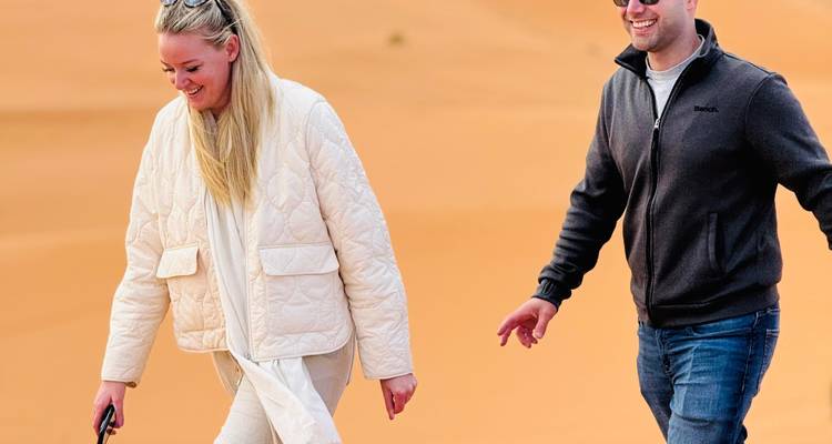 Turistas sonrientes caminando sobre dunas de arena en Marruecos.