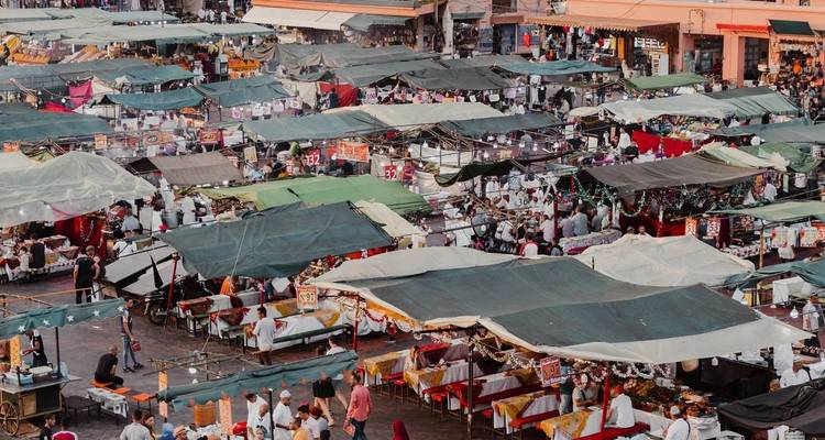 Zone de marché avec divers étals couverts de bâches vertes.