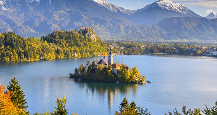 Insel mit einer Kirche, umgeben von einem See und Bergen.