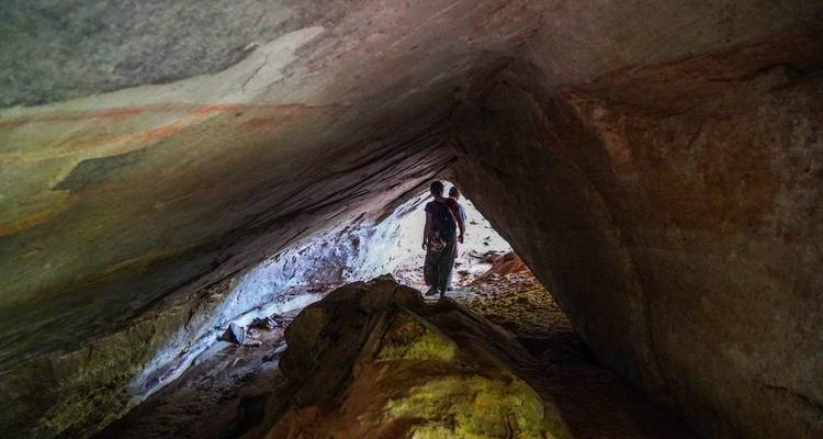 Persona de pie dentro de una cueva rocosa o túnel natural.