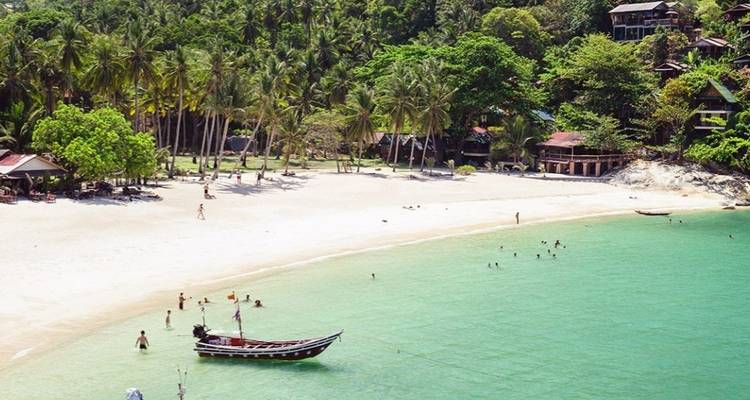 Tropisch strand met mensen die ontspannen en een boot bij de kust.