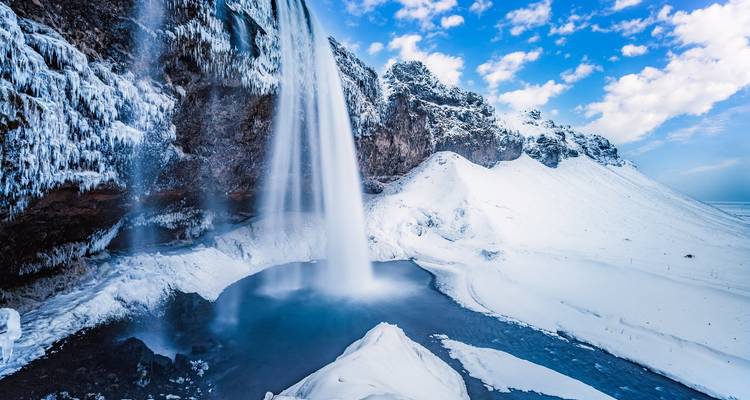 Waterfall cascading over icy cliffs into a frozen pool.