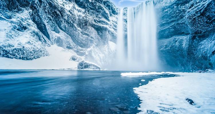 Majestic waterfall surrounded by icy cliffs and frozen landscape.