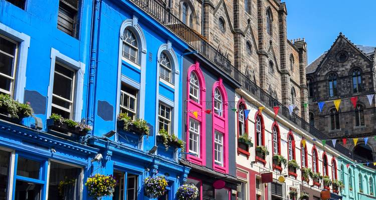 A colorful row of boutique storefronts and stone buildings along Victoria Street in bright daylight.