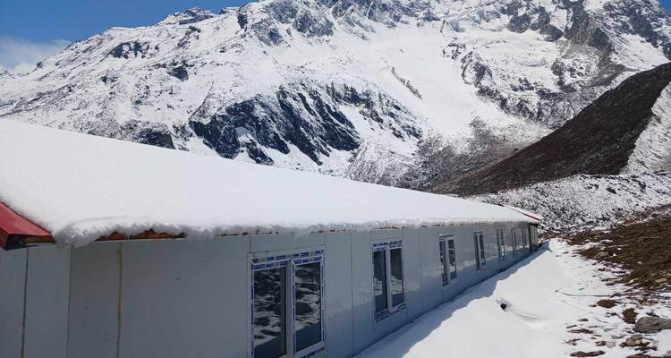 Bâtiment avec un toit couvert de neige sur fond de montagnes.