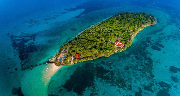 Luftaufnahme einer Insel mit Grünflächen und blauem Wasser.