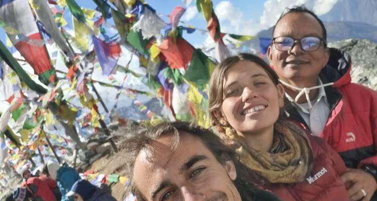 Menschen, die mit Gebetsfahnen in einem bergigen Gebiet posieren.