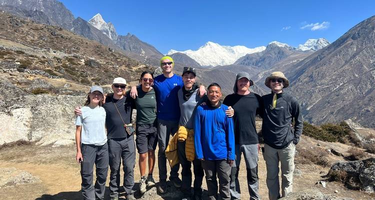Group of trekkers posing with a panoramic mountain view.