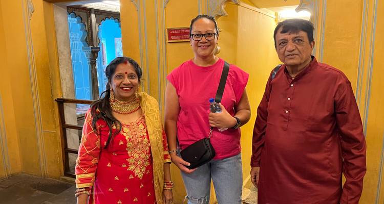 Drei Besucher posieren in einem lebhaft bemalten Palastkorridor mit gelben Wänden und traditionellen Bögen.