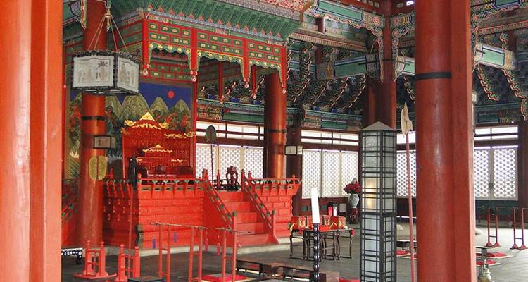 Intérieur de la salle du trône peint de couleurs vives avec des colonnes rouges ornées et des motifs coréens complexes