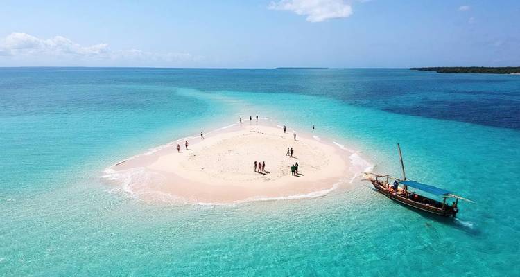 Groep mensen op een klein zandig eiland met een boot