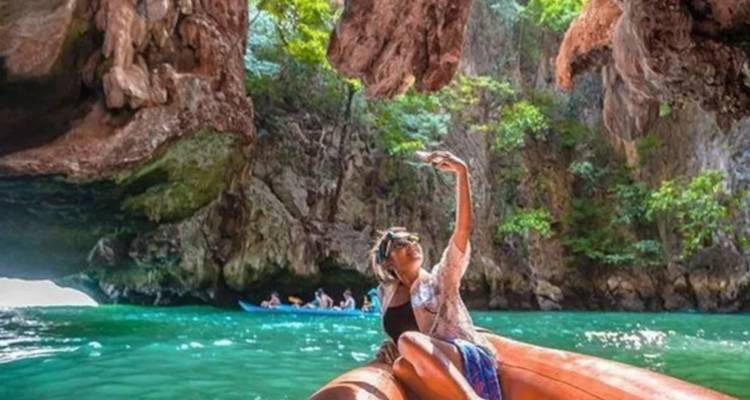 Frau macht ein Selfie auf einem Boot in einer abgelegenen, tropischen Höhle.