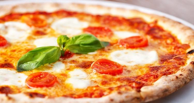 Gros plan d'une pizza Margherita avec du basilic frais.