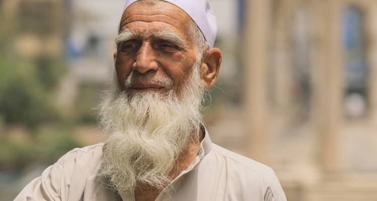 Elderly man with a white beard in traditional attire.

German translation: Älterer Mann mit weißem Bart in traditioneller Kleidung.