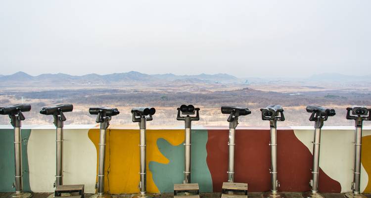 Row of industrial binoculars pointed towards a vast landscape.