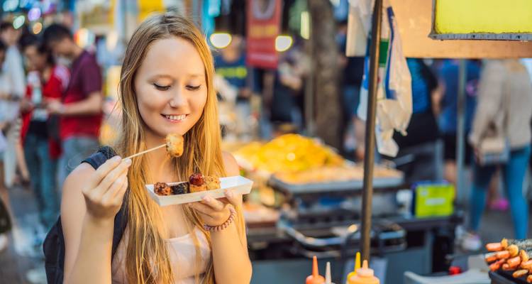 Person enjoying street food at a market stall.
