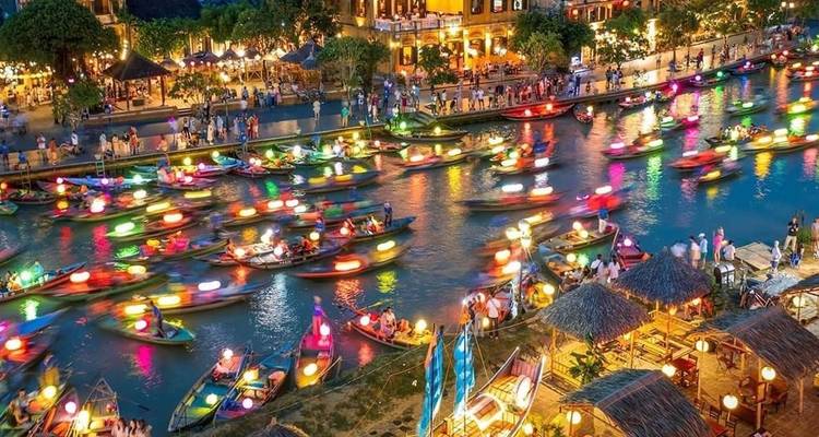 Festival met boten op een rivier verlicht door kleurrijke lantaarns.