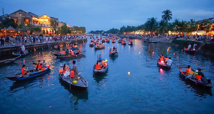 Mensen op boten die genieten van een nachtfestival op een rivier.