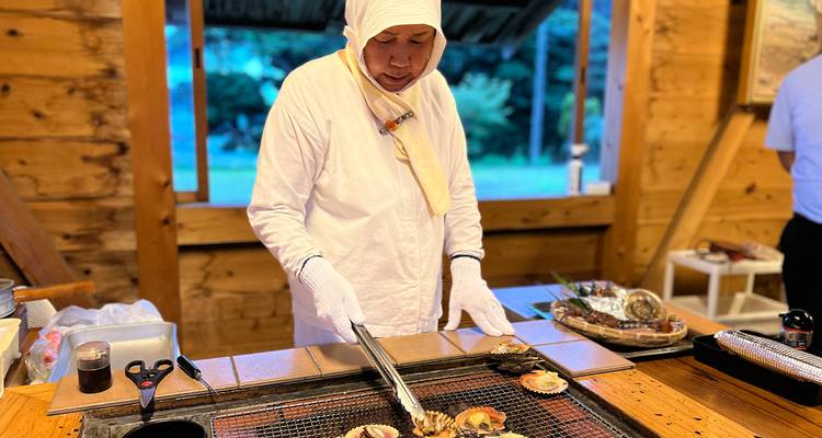 Chef in traditional attire grilling seafood.
