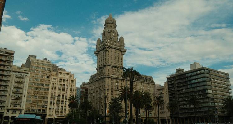 Historic Palacio Salvo and surrounding buildings against a blue sky with scattered clouds in Montevideo
