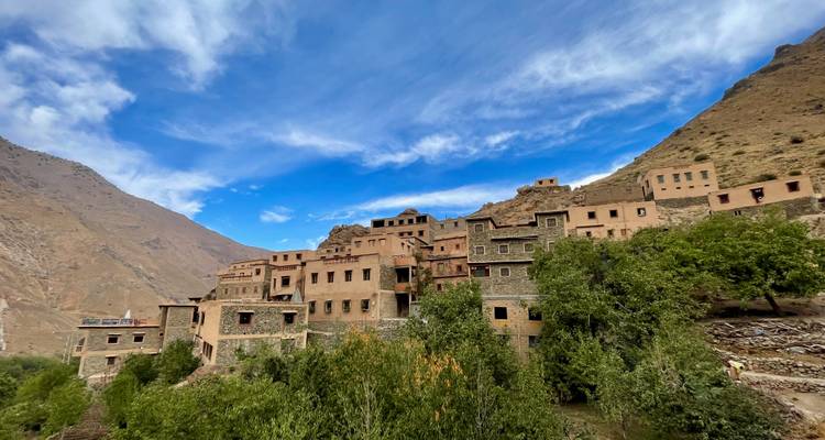 Las casas de piedra y adobe se deslizan por la ladera de una montaña verde bajo un cielo azul vibrante.