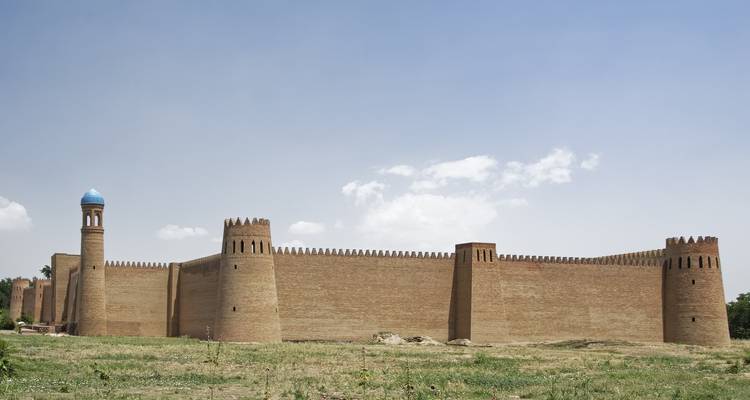 Große antike Festung mit hohen braunen Mauern vor einem bewölkten Himmel.