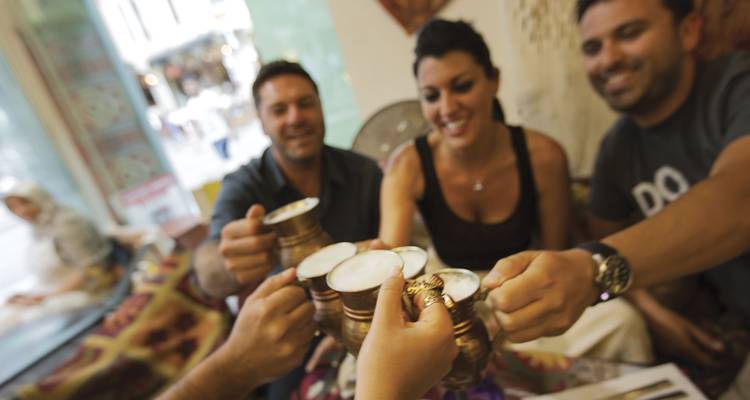 Des amis lèvent des tasses en cuivre ornées remplies d'une boisson mousseuse dans un café douillet.